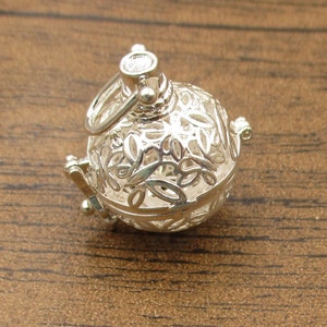 Puede incluir: Encanto de plata con un delicado y complejo diseño de hojas y flores. El encanto es hueco y tiene una pequeña abertura en la parte superior para sujetarlo a un collar o pulsera.