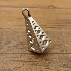 以下が含まれることがあります： 幾何学模様の銀色の金属製のピラミッド型のペンダント。ペンダントの上部にチェーンやコードを取り付けるためのループがあります。