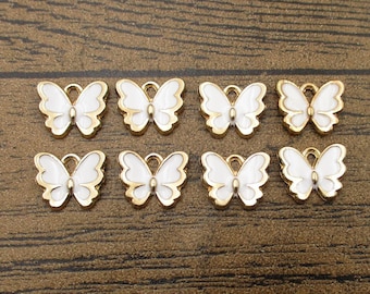 May include: Eight gold-colored butterfly charms with white enamel wings. The charms have a loop at the top for attaching to jewelry or other crafts.