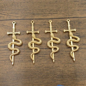 May include: Four gold-coloured metal charms in the shape of a sword with a snake wrapped around it. The snake's head is at the top of the sword and its tail is at the bottom.