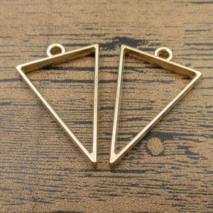 May include: Two gold-tone triangle-shaped pendant frames with a loop at the top for hanging.