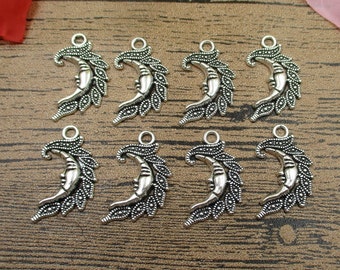 May include: Seven silver-toned metal charms in the shape of a crescent moon with a face and ornate details. The charms have a loop at the top for attaching to jewelry or other crafts.