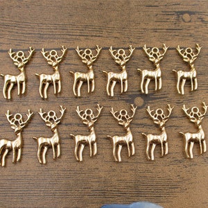 May include: A set of 16 gold-colored metal reindeer charms. The charms are about 1 inch tall and have a loop at the top for attaching to a necklace, bracelet, or other jewelry.