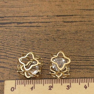 May include: Two gold-tone hair clips with clear crystal stones in the center. The clips are shaped like a star and are about 1 inch in diameter.
