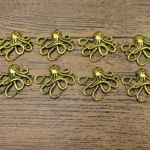May include: Ten gold-toned octopus charms with intricate details. Each charm features a detailed octopus design with eight tentacles.