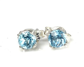 May include: A pair of silver stud earrings with round, light blue topaz gemstones.
