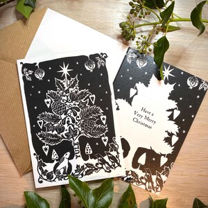 K&ouml;nnte beinhalten: Schwarz-wei&szlig;e Weihnachtskarten mit einem festlichen Baumdesign, einem Hasen und dem Wort "Yule". Eine Karte lautet "Have a Very Merry Christmas". Mit einem wei&szlig;en und einem braunen Umschlag.
