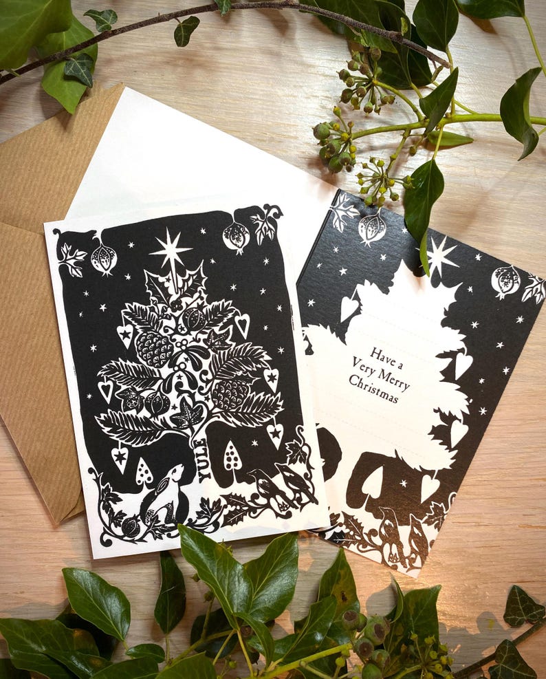 K&ouml;nnte beinhalten: Schwarz-wei&szlig;e Weihnachtskarten mit einem festlichen Baumdesign, einem Hasen und dem Wort "Yule". Eine Karte lautet "Have a Very Merry Christmas". Mit einem wei&szlig;en und einem braunen Umschlag.