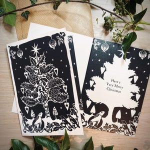 K&ouml;nnte beinhalten: Schwarz-Wei&szlig;-Weihnachtskarten mit einem festlichen Baumdesign, mit Sternen, Herzen und botanischen Elementen. Eine Karte lautet "Have a Very Merry Christmas". Enth&auml;lt Umschl&auml;ge und dekoratives Gr&uuml;n.