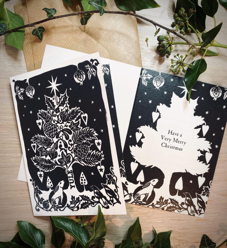 K&ouml;nnte beinhalten: Schwarz-Wei&szlig;-Weihnachtskarten mit einem festlichen Baumdesign, mit Sternen, Herzen und botanischen Elementen. Eine Karte lautet "Have a Very Merry Christmas". Enth&auml;lt Umschl&auml;ge und dekoratives Gr&uuml;n.