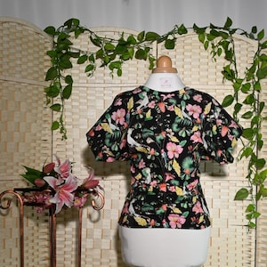 Op de afbeelding: Zwart-witte bloemenprint blouse met korte mouwen en een gerimpelde halslijn. De blouse heeft een getailleerd bovenlichaam en een losse, vloeiende pasvorm.