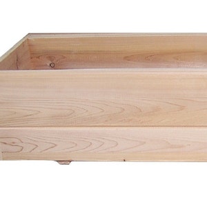 May include: A rectangular wooden planter box with a natural wood finish. The box is constructed from horizontal planks and features a beveled edge. The planter is designed for outdoor use and has a simple, rustic aesthetic.
