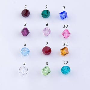 May include: Twelve different colored glass beads, each with a number from 1 to 12. The beads are arranged in four rows of three beads each.