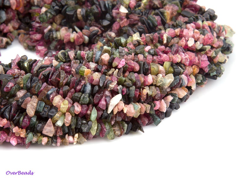 May include: A strand of multi-colored tourmaline gemstone chips. The chips are a mix of pink, green, black, and brown.