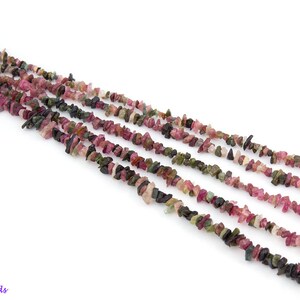 May include: A strand of multi-colored tourmaline chip beads. The beads are a mix of pink, green, and black.