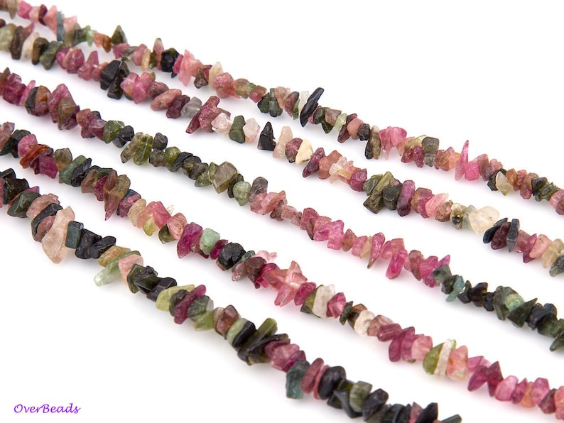 May include: A strand of multi-colored gemstone chips, including pink, green, and black, arranged in a row. The chips are irregular in shape and size, and they are strung together on a clear thread.