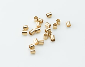 May include: A scattering of gold-colored metal jump rings on a white surface.