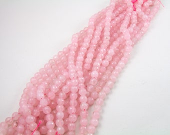 Può includere: Una collana di perle di quarzo rosa. Le perle sono sfaccettate e hanno una forma naturale leggermente irregolare. Le perle sono infilate su un filo sottile e trasparente.