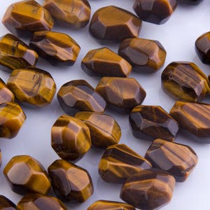 May include: A strand of brown and gold tiger's eye gemstone beads. The beads are faceted and have a natural, irregular shape.