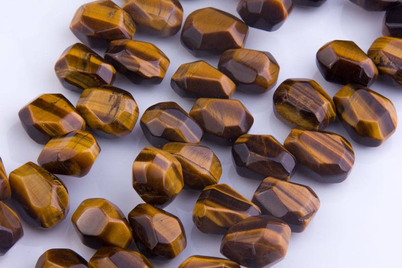 May include: A strand of brown and gold tiger's eye gemstone beads. The beads are faceted and have a natural, irregular shape.