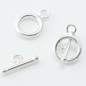 May include: Silver toggle clasp with a round ring and a bar with two round ends.