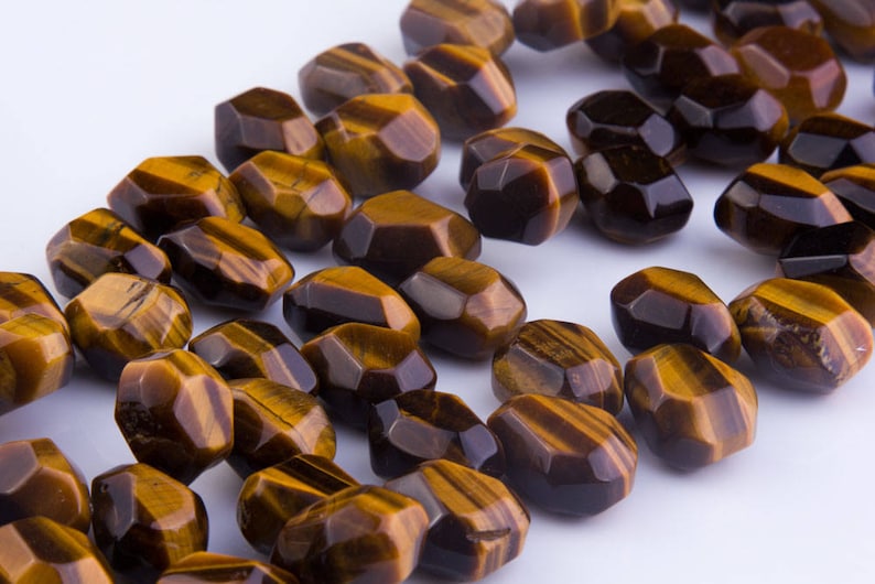 May include: A strand of faceted tiger's eye beads in shades of brown and gold. The beads are all faceted and have a slightly irregular shape.