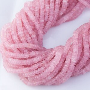 May include: A strand of pink rose quartz beads, each bead is faceted and has a square shape.