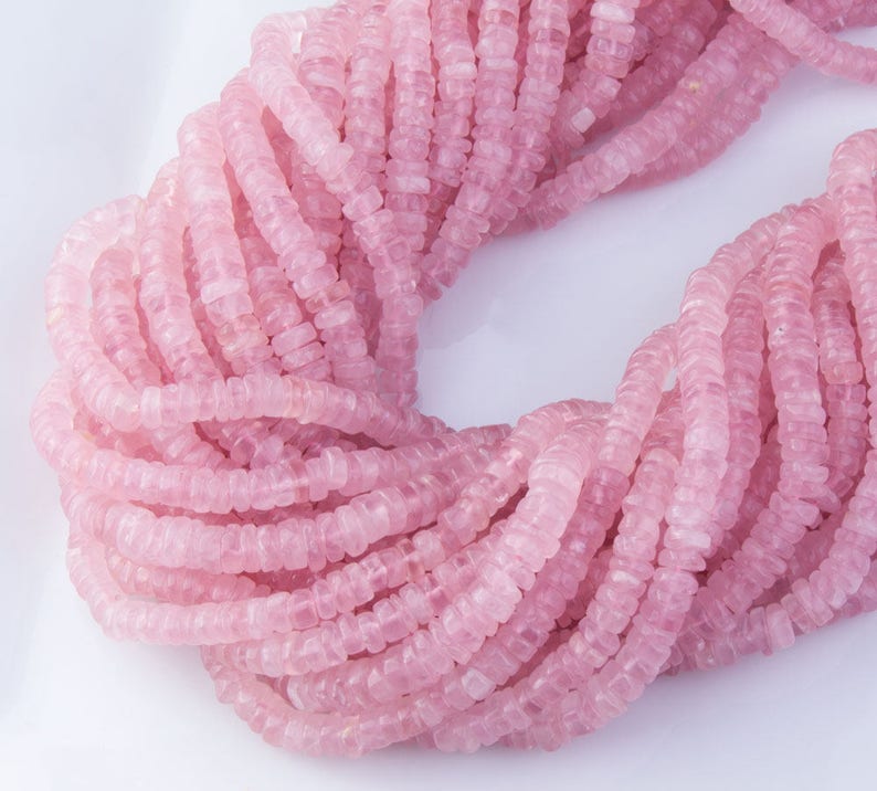 May include: A strand of pink rose quartz beads, each bead is faceted and has a square shape.