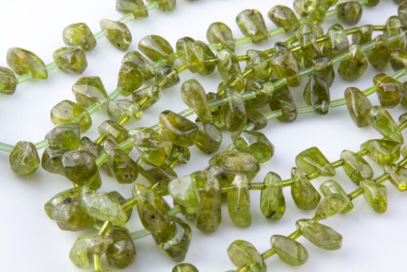 Puede incluir: Una hebra de cuentas de piedras preciosas verdes, cada cuenta tiene una forma irregular y &uacute;nica. Las cuentas est&aacute;n enhebradas en un hilo transparente.