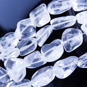 Pode incluir: Um fio de contas de cristal de quartzo transparente, cada conta &eacute; facetada e tem um acabamento liso e polido. As contas s&atilde;o dispostas em um padr&atilde;o solto e fluido, criando uma sensa&ccedil;&atilde;o de movimento e energia.