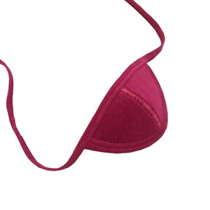 May include: A maroon triangle bikini top with a stitched edge and a thin strap. The top is made of a soft material and is set against a white background.