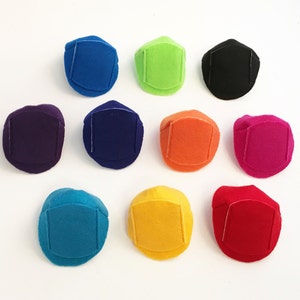 May include: A collection of ten felt dice in various colors, including blue, green, black, purple, navy, orange, pink, teal, yellow, and red. Each die has a square patch on one side.