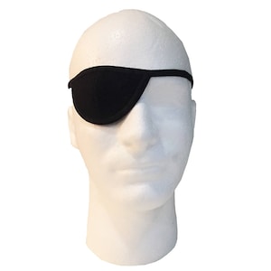 May include: A black eye patch made of soft material, designed to cover one eye. The eye patch is held in place by a thin black strap that goes around the head. The eye patch is displayed on a white mannequin head.