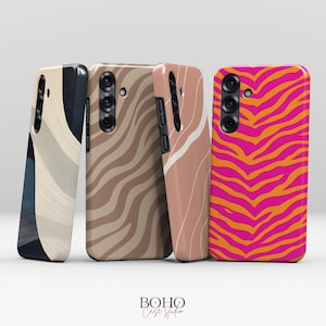 Könnte beinhalten: Vier Handyhüllen mit einzigartigen Designs. Eine Hülle zeigt ein beiges und marineblaues abstraktes Muster, eine andere einen braunen Zebrastreifen, eine dritte ein rosa-weißes Design und die letzte ein rosa-oranges Zebrastreifenmuster. Die Hüllen stammen von Boho Case Studio.