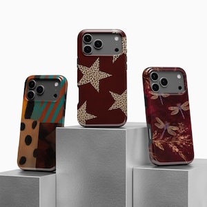 Op de afbeelding: Drie telefoonhoesjes met unieke ontwerpen. Eén hoesje heeft een patchwork-ontwerp met oranje, turquoise en bruine kleuren. Een andere heeft een bordeauxrode achtergrond met sterren in luipaardprint. De derde hoes heeft een bordeauxrode achtergrond met libellen- en bloempatronen.