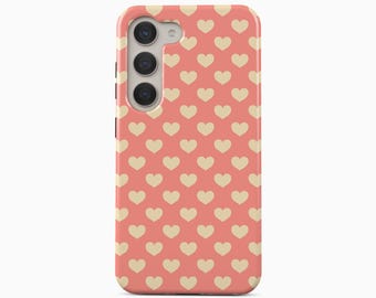 May include: A smartphone case featuring a repeating pattern of small, light beige hearts set against a solid coral pink background. The case includes a vertical camera cutout on the upper left side with three circular lenses and a small flash component.