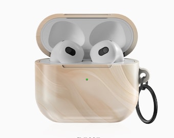 Może przedstawiać: Etui na słuchawki AirPods w kolorze beżowym i brązowym z imitacją drewna, z przymocowanym czarnym kółkiem. Etui jest otwarte, a białe słuchawki AirPods są widoczne.