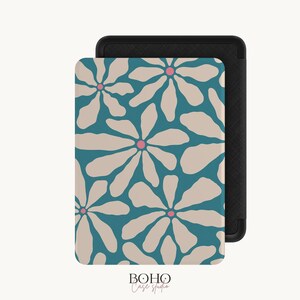 Op de afbeelding: Een rechthoekige e-reader hoes met een blauwgroene achtergrond en een herhalend patroon van grote, lichtbeige bloemblaadjes en kleine roze centra. De hoes heeft een zwarte, getextureerde rand en de tekst Boho Case Studio staat eronder vermeld.