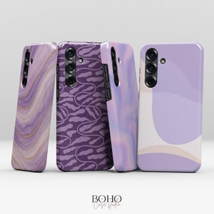 Może przedstawiać: Cztery etui na telefon z unikalnymi wzorami w odcieniach fioletu. Wzory obejmują marmur, abstrakcyjne wiry i powtarzający się motyw. Etui pochodzą z Boho Case Studio. Projekty zawierają złoto i inne kolory.