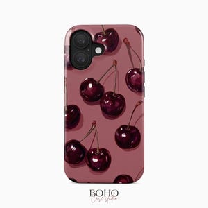 Może przedstawiać: Etui na telefon z wzorem ciemnoczerwonych wiśni z zielonymi łodygami na tle w kolorze malwy. Etui posiada wycięcie na aparat i napis "BOHO Case studio".