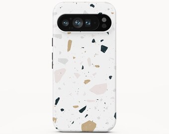 May include: A white smartphone case featuring a multi-coloured terrazzo pattern with scattered geometric shapes in shades of tan, light pink, dark grey, and light grey. The case has a black horizontal camera cutout at the top and the text BOHO Case studio.