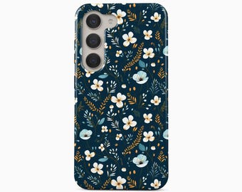 May include: A dark navy blue smartphone case featuring a repeating pattern of small white flowers, light blue petals, and golden-brown fern-like foliage. The case includes a cutout for a triple-lens camera system on the upper left side.