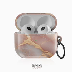 May include: A pink and gold marble patterned case for AirPods with a gold chain attached. The case is open, revealing the white AirPods inside.