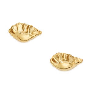 May include: A pair of gold-toned earrings shaped like a dumpling. The earrings are small and delicate, and they would make a great gift for a food lover.