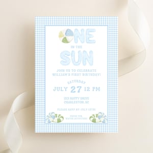 Könnte beinhalten: Eine hellblaue Einladung mit Vichy-Muster und den Worten "ONE IN THE SUN" in großen, verspielten Buchstaben. Die Einladung kündigt eine Geburtstagsfeier am 27. Juli um 12 Uhr an, mit einem Dresscode für Wasseraktivitäten.