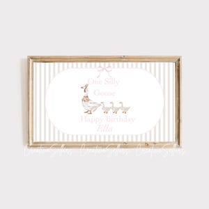 May include: A white framed print with a gray and white striped background. The print features a white goose with pink accents and three smaller geese following behind. The text reads "One Silly Goose Happy Birthday Ella".
