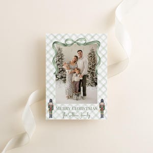 May include: A Christmas card with a family photo framed by a green plaid pattern and a green ribbon. The card reads "Merry Christmas" and "The Sellers Family". Two toy soldier illustrations are at the bottom.