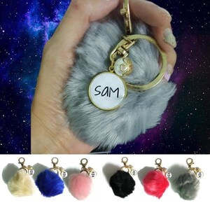 May include: A set of six fluffy keychains with a personalised name tag. The keychains are available in six colours: cream, blue, pink, black, red, and grey. Each keychain features a small charm with the text "You are loved".