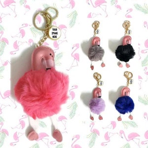 May include: Flamingo keyrings with fluffy bodies, pink heads, and gold-coloured hardware. The keyrings have a round charm that says "YOUR IMAGE HERE". Additional keyrings in grey, black, purple, and blue are also shown.