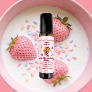 May include: A rollerball perfume bottle with a pink label featuring a cartoon character, the text Sugar Milk Co. Milk Strawberry Baby, and 10 mL. The bottle is positioned over a pink bowl filled with milk, three strawberries, and colourful sugar sprinkles.